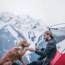 man camping on mountain with dog