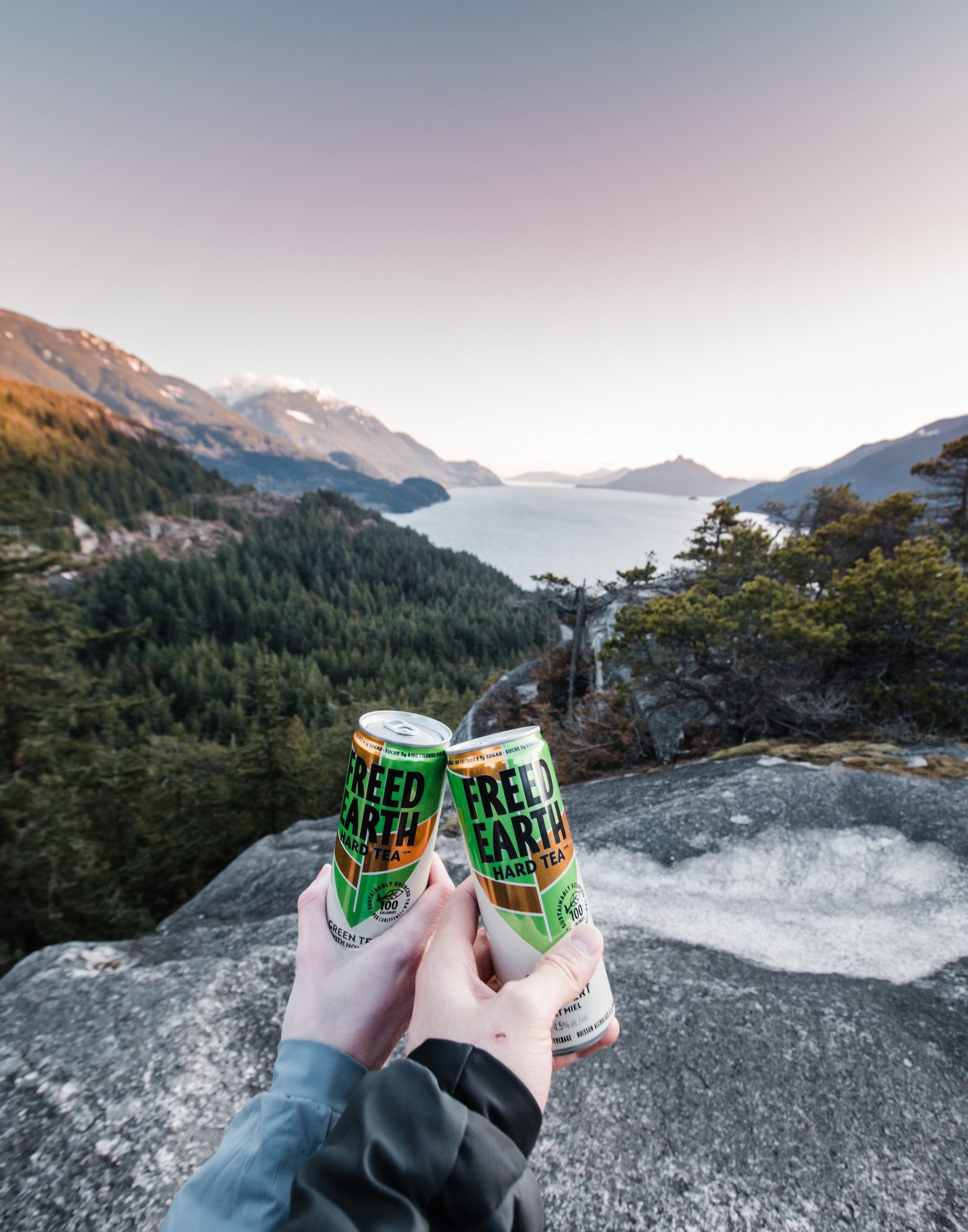 two people drinking while looking out at mountains