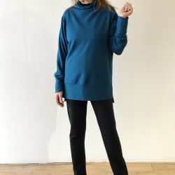 The model is wearing a sweater that goes past her hips, in Moroccan blue