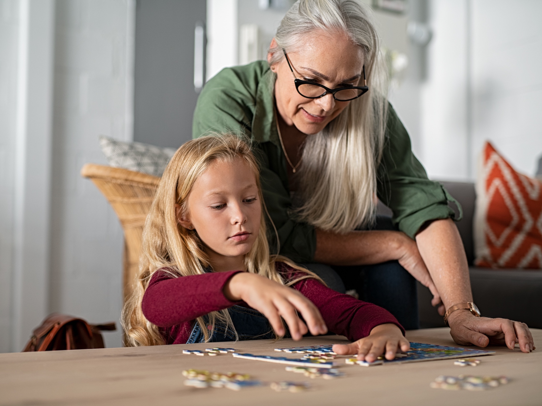 Girl doing jigsaw puzzle with grandmother