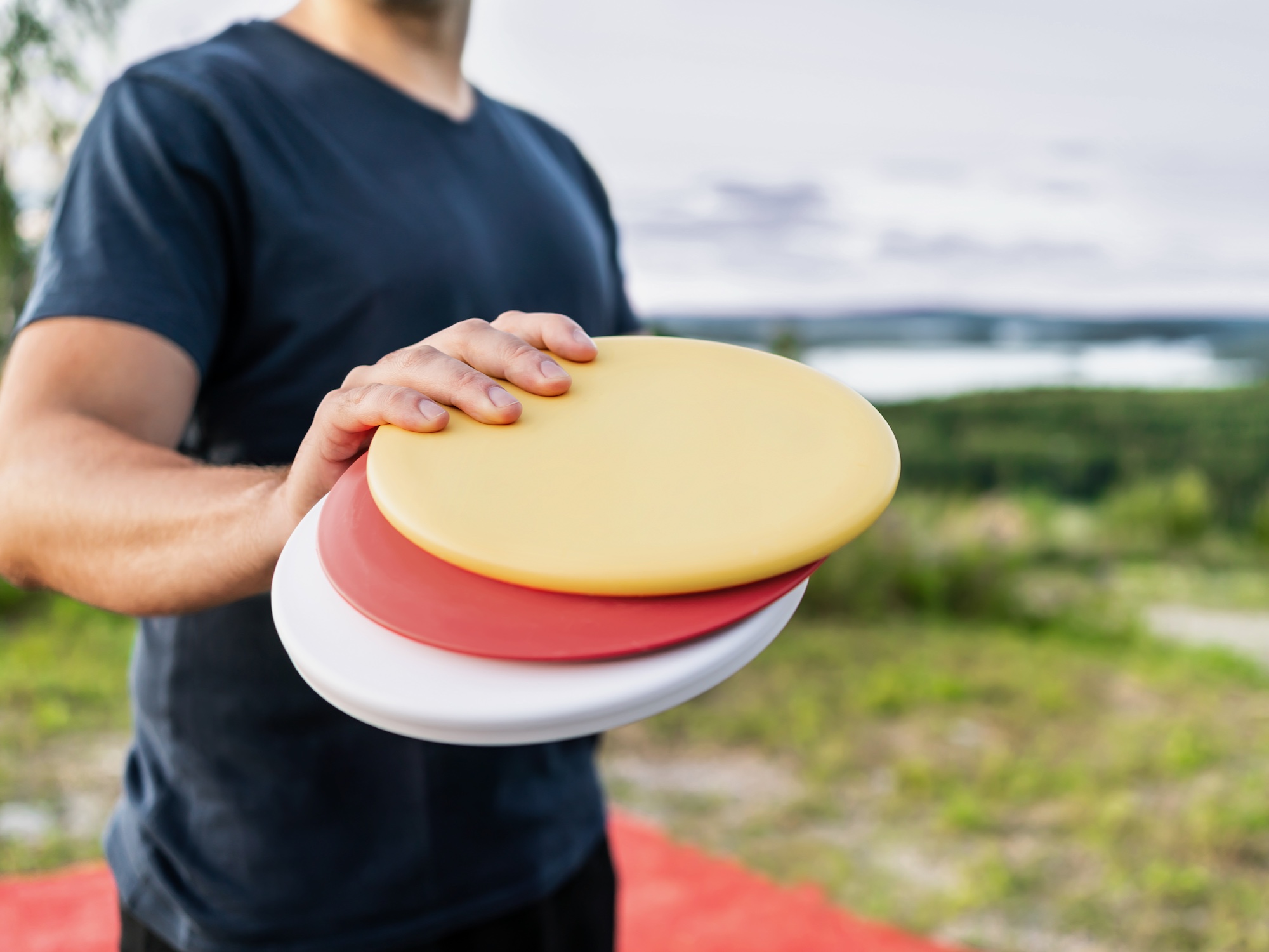 Disc golf player with frisbee equipment in park course. Man playing discgolf. Outdoor sport tournament. Summer landscape in Finland.