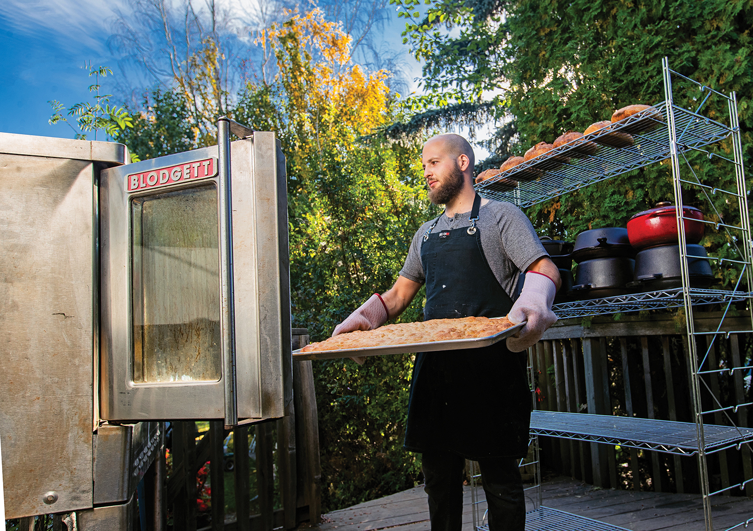Benny taking out a tray of foccacia bread from his outside oven