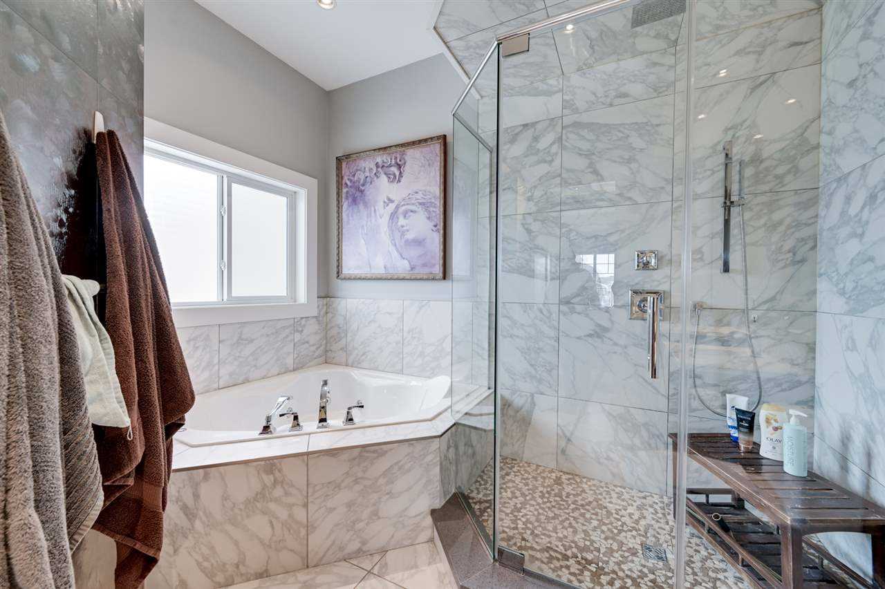 Marble en suite bathroom; large glass shower next to embedded tub under window