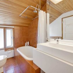 Wood floor, ceiling and walls; white sinks, toilet and tub with free-hanging curtain. 