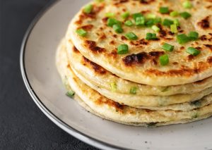 Chinese green onion pancakes on a black background.