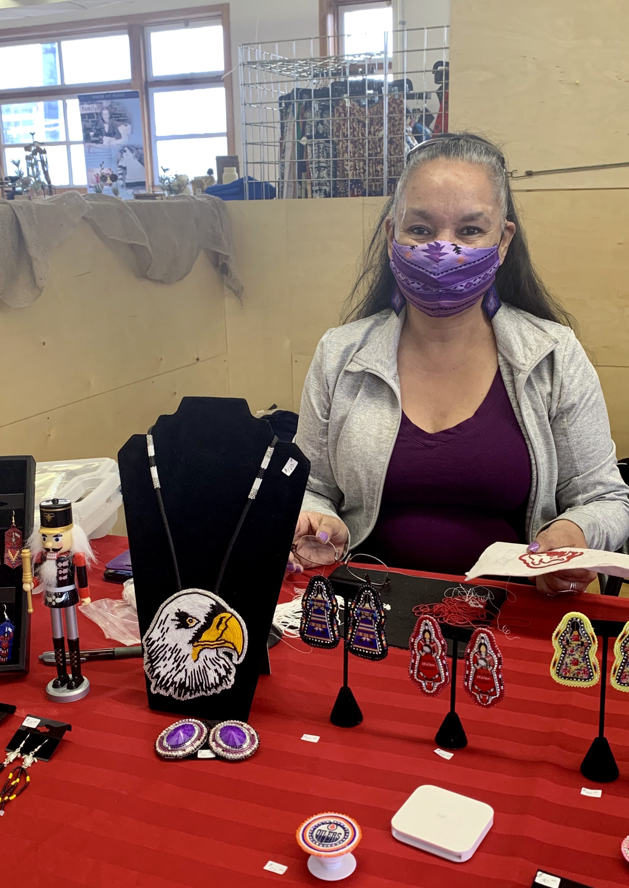 A lady standing behind her table, selling indigenous art and jewelry 