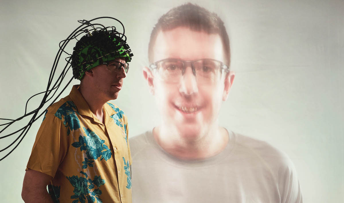 Kyle Mathewson_FuzzyBackgroundHeadShot_KyleWearingCapWithLotsOfCordsInFront 2