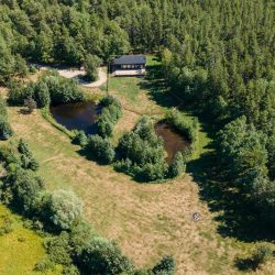 Overhead view of black seacan home and land with two small ponds surrounded by trees