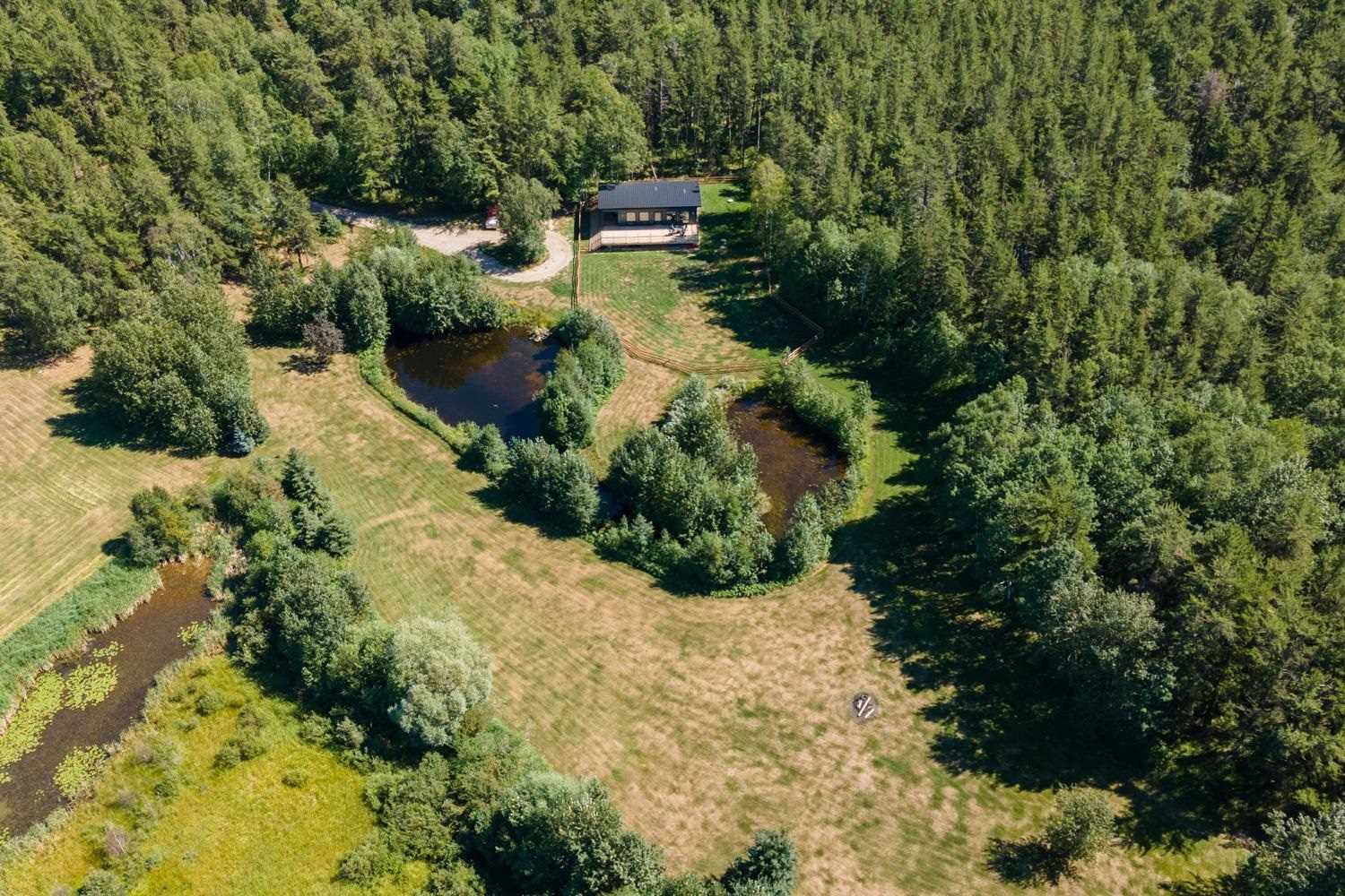 Overhead view of black seacan home and land with two small ponds surrounded by trees