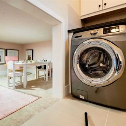 Laundry room, with grey and silver clothes dryer, opening to a half-height kids' crawl space with tea party decor