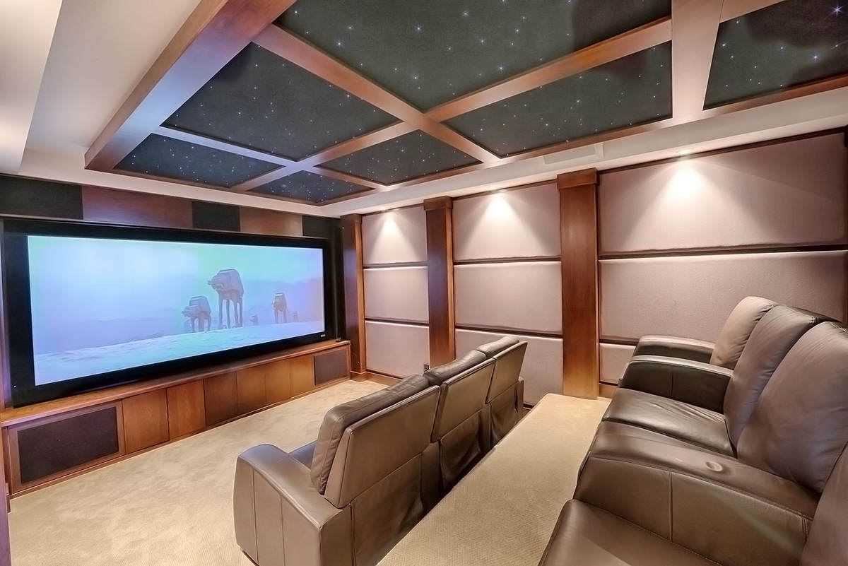 Interior movie room with wood coffered ceiling, stadium seating with grey recliners; Star Wars' AT-AT Walkers on screen