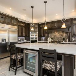 Kitchen with white ceiling and white marble floor; dark maple cabinets; island with with countertop, sink and mini-fridge
