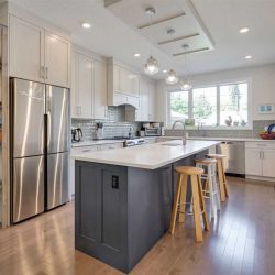 Kitchen, steel fridge, L-shaped counter, large window. 